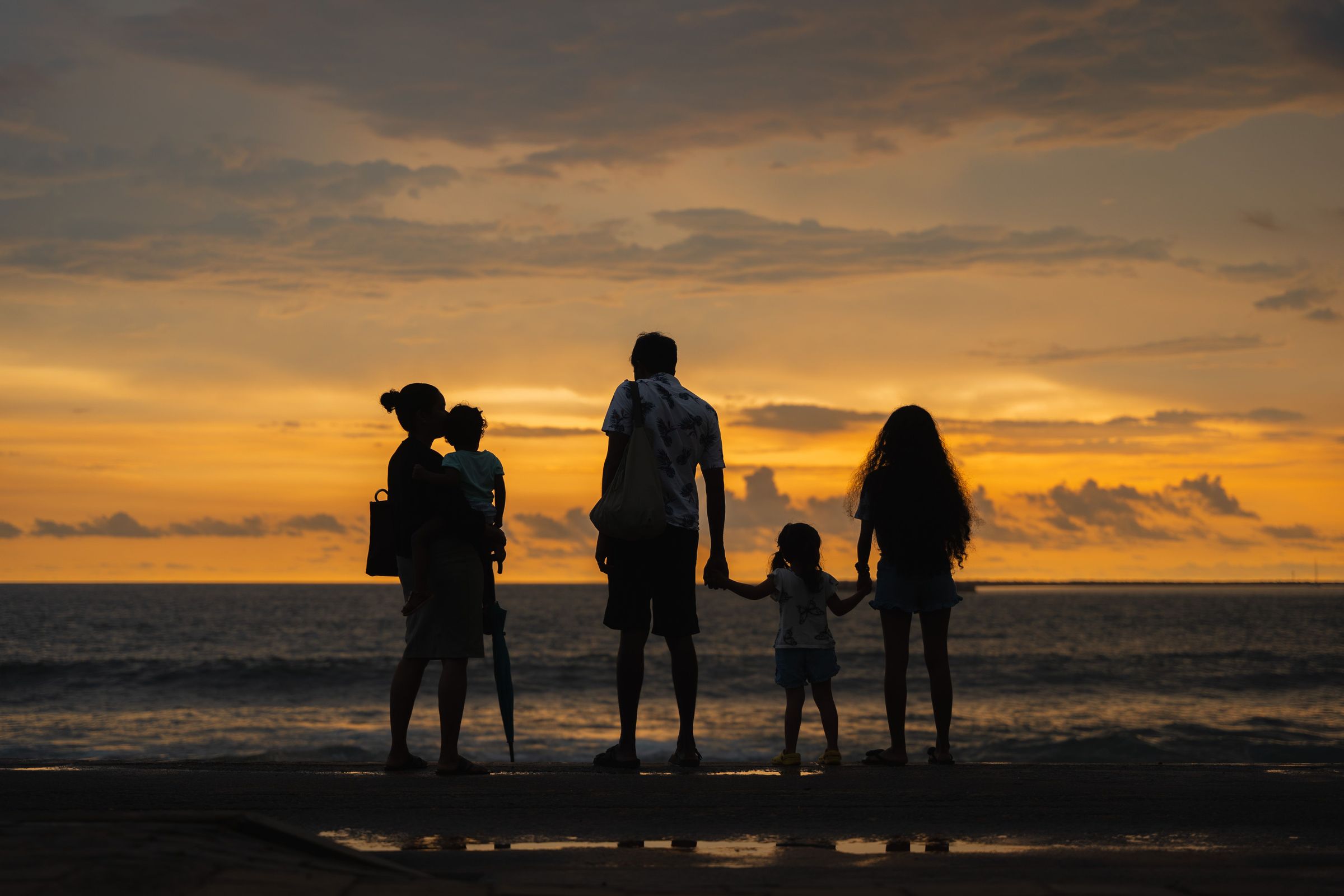 A mother, a father and their three children on the beach at sunset